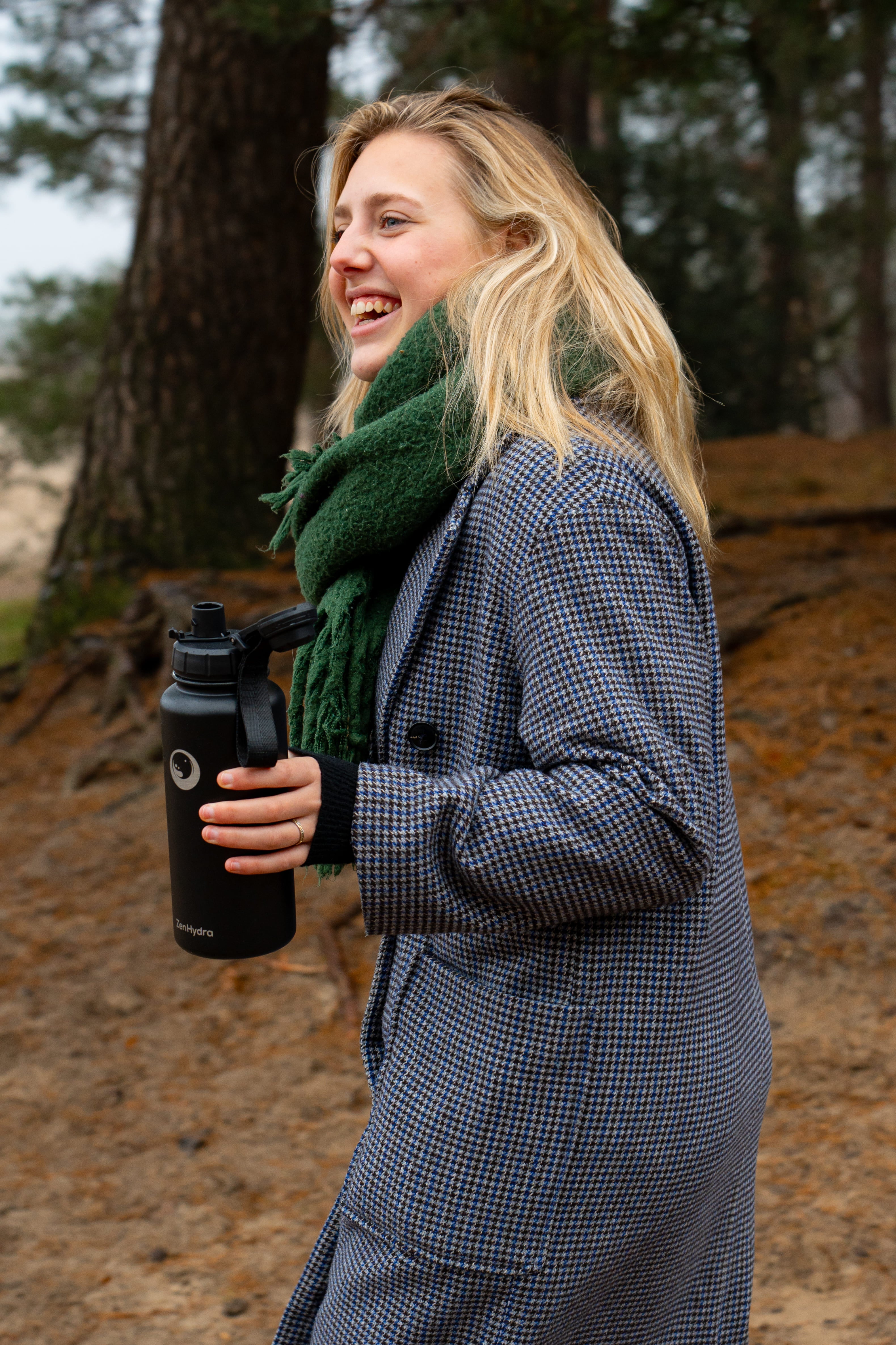 Vrouw met zwarte Zenhydra fles in het bos