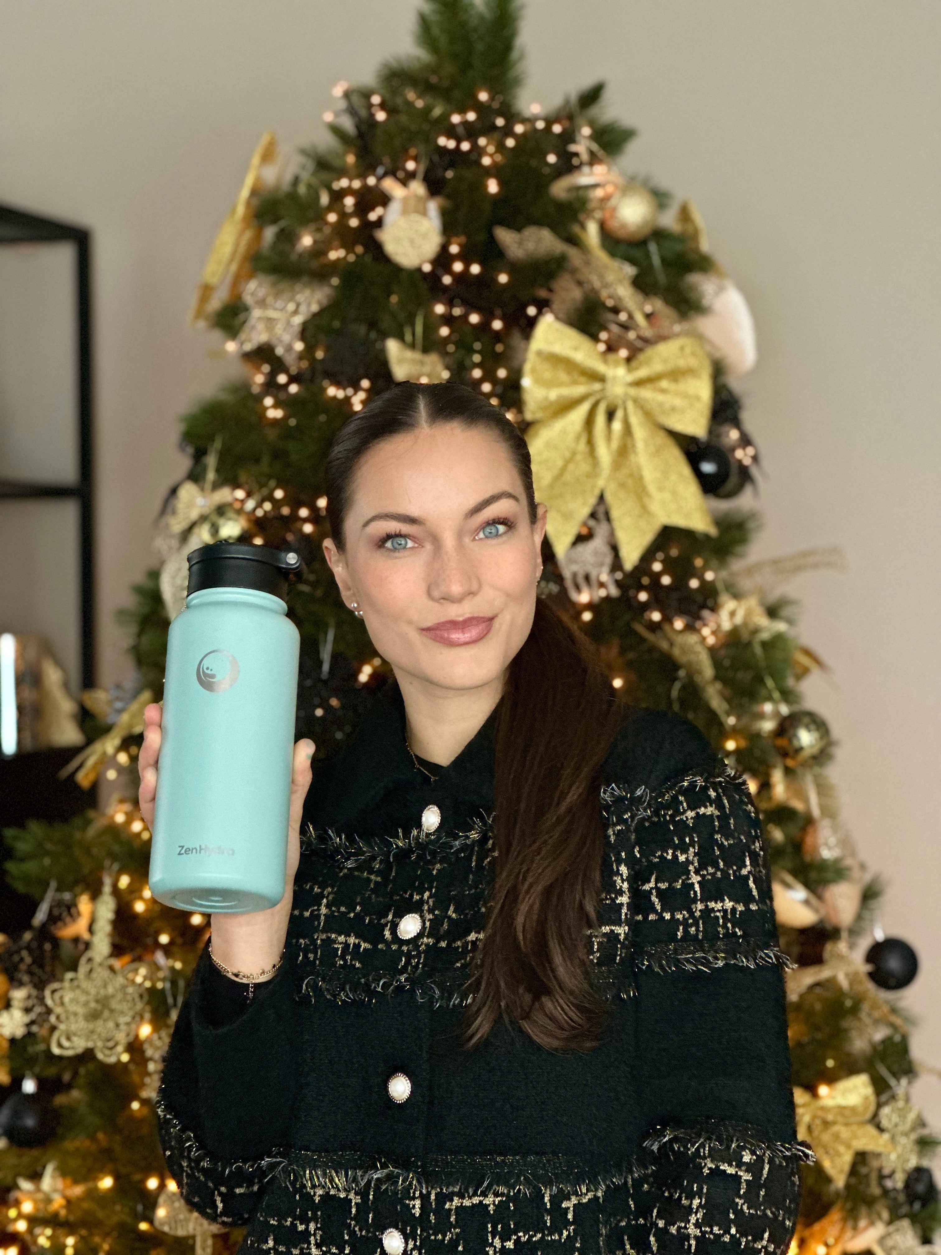 Vrouw met groene Zenhydra fles voor een kerstboom