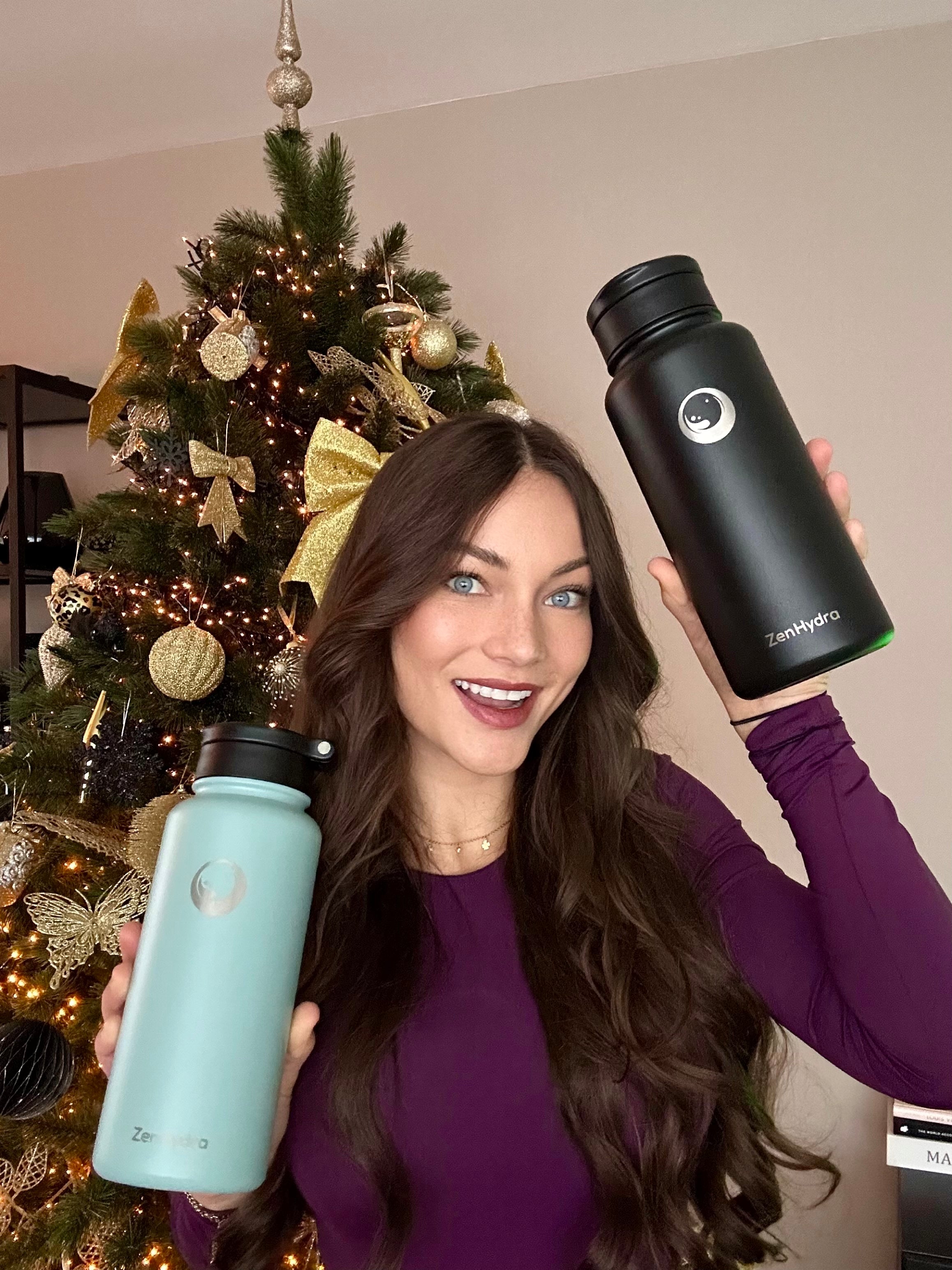 Vrouw met 2 Zenhydra drinkflessen voor een kerstboom